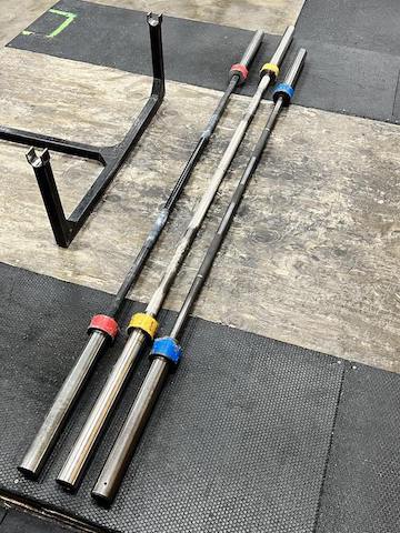 What is a barbell? Here is a squat bar, deadlift bar, and power barbell on a lifting platform.